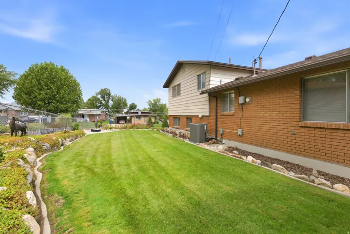 Expansive grassy rear backyard with defined rock-lined landscaping