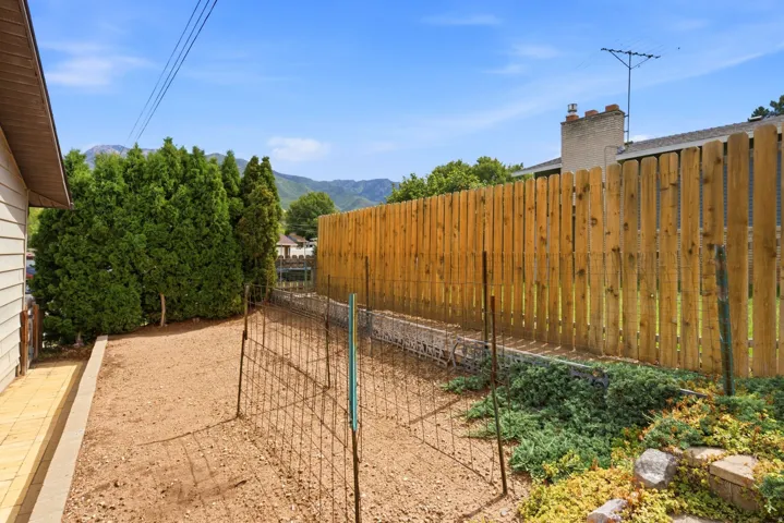 East exterior garden located next to the garage, wood fencing, and established evergreens
