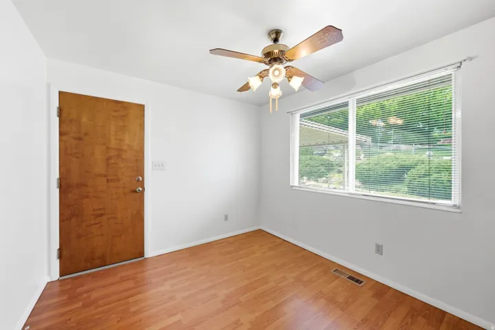 Main level kitchen with door access to garage, vinyl (LVP) flooring, white walls, ceiling fan with integrated lighting, and window with blinds