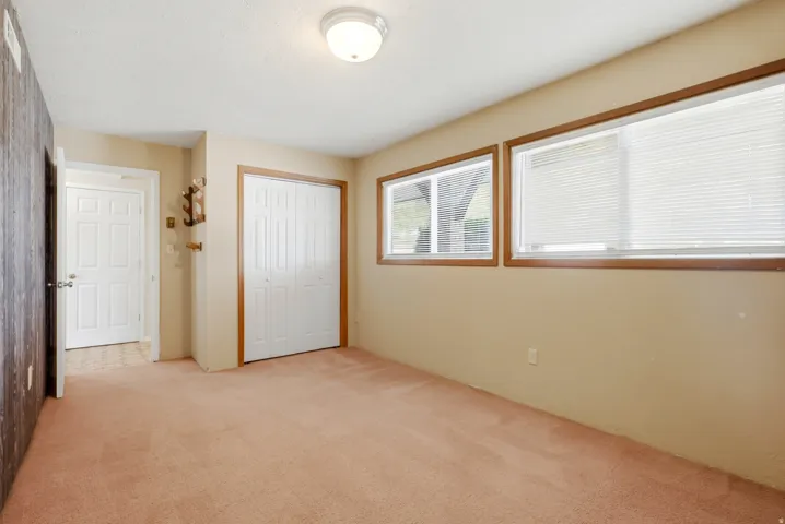 Two horizontal windows with blinds, bi-fold closet doors, and recessed lighting