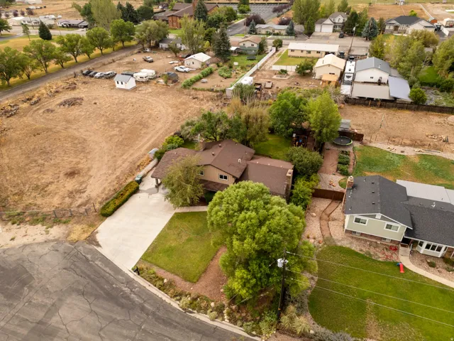 Property featuring a brown shingle roof, paved driveway, and manicured front lawn