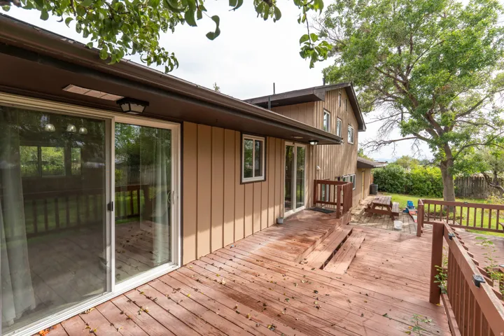 Expansive wood-finish deck with integrated steps, multiple sliding glass doors, and durable siding
