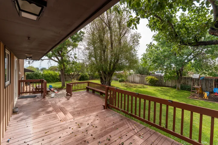 Expansive wooden deck with built-in bench seating, wood railing, and overhead lighting