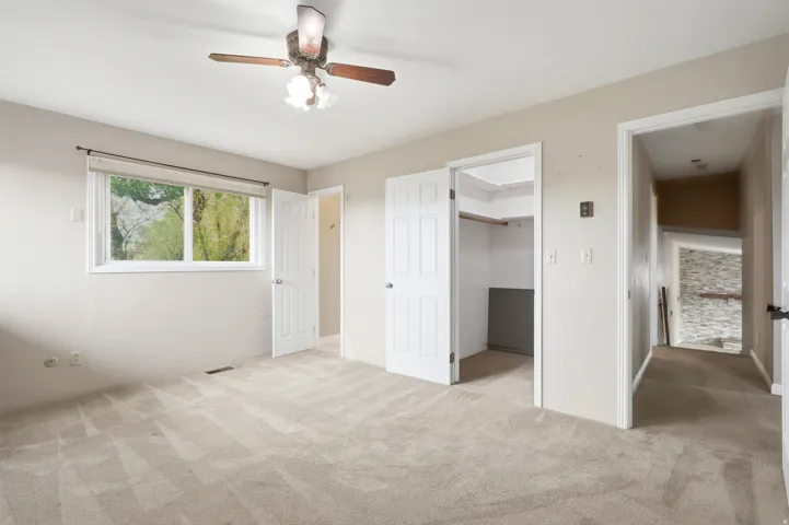 Wall-to-wall carpeted flooring, window with natural light, ceiling fan with integrated lighting, and closet with built-in shelving
