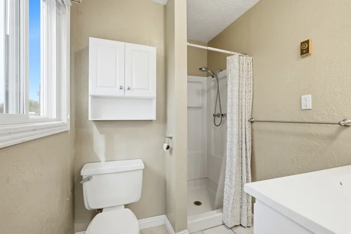 White toilet, built-in white shower stall, and white cabinetry