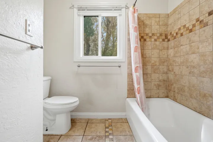 Built-in bathtub with tiled surround featuring a decorative accent band