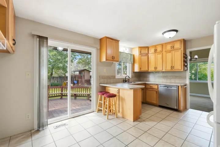 Kitchen featuring wood-finish cabinetry, stainless steel dishwasher, tile flooring, and a sliding glass door