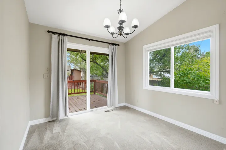 Vaulted ceiling, chandelier, window, sliding glass door, and exterior wooden deck