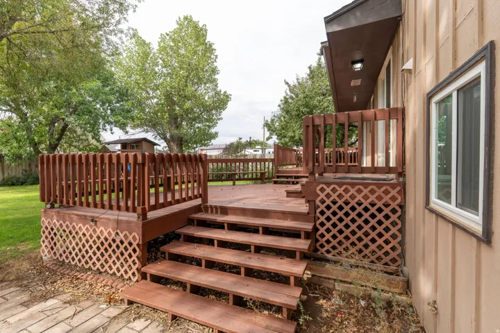 Multi-tiered wood deck featuring lattice skirting, wood railings, and a direct entrance to the residence