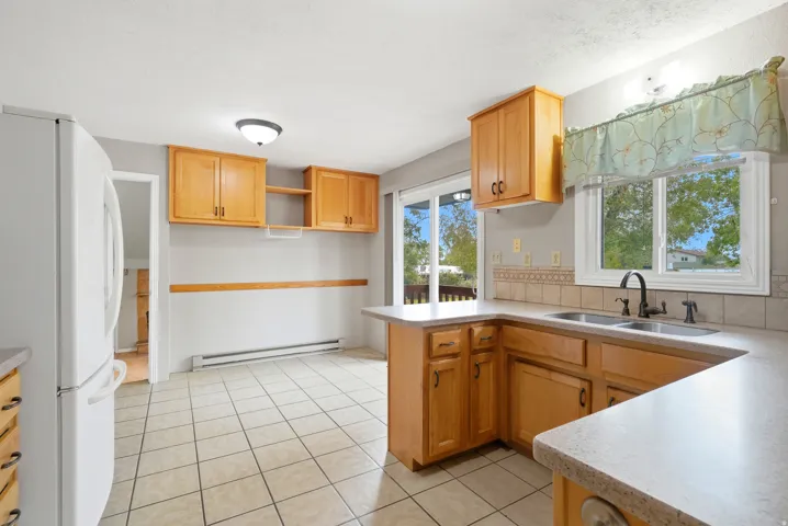 Kitchen featuring wood-finish cabinetry, light-toned countertops, and tile flooring