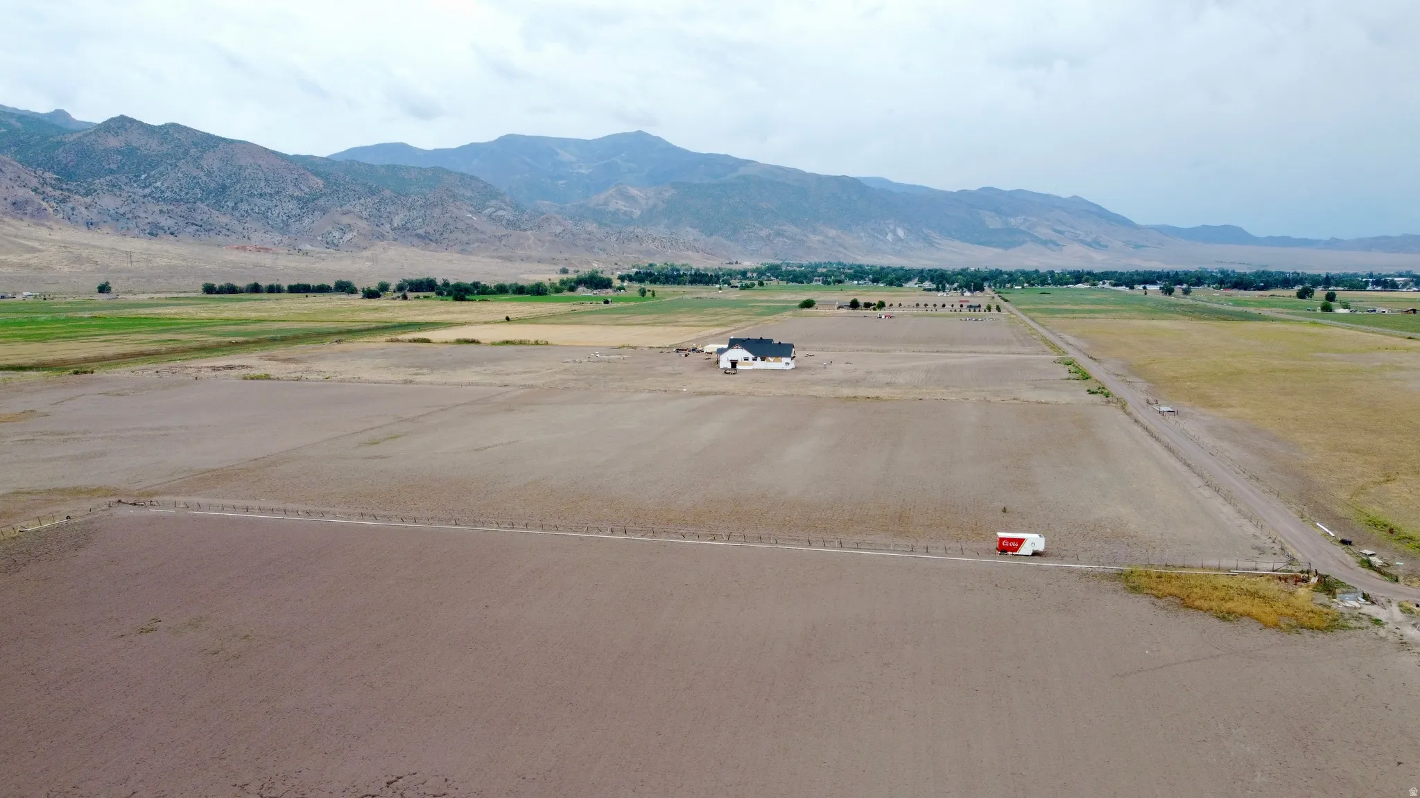 Expansive land parcel featuring a contemporary single-story residence with a dark roof and a paved access road