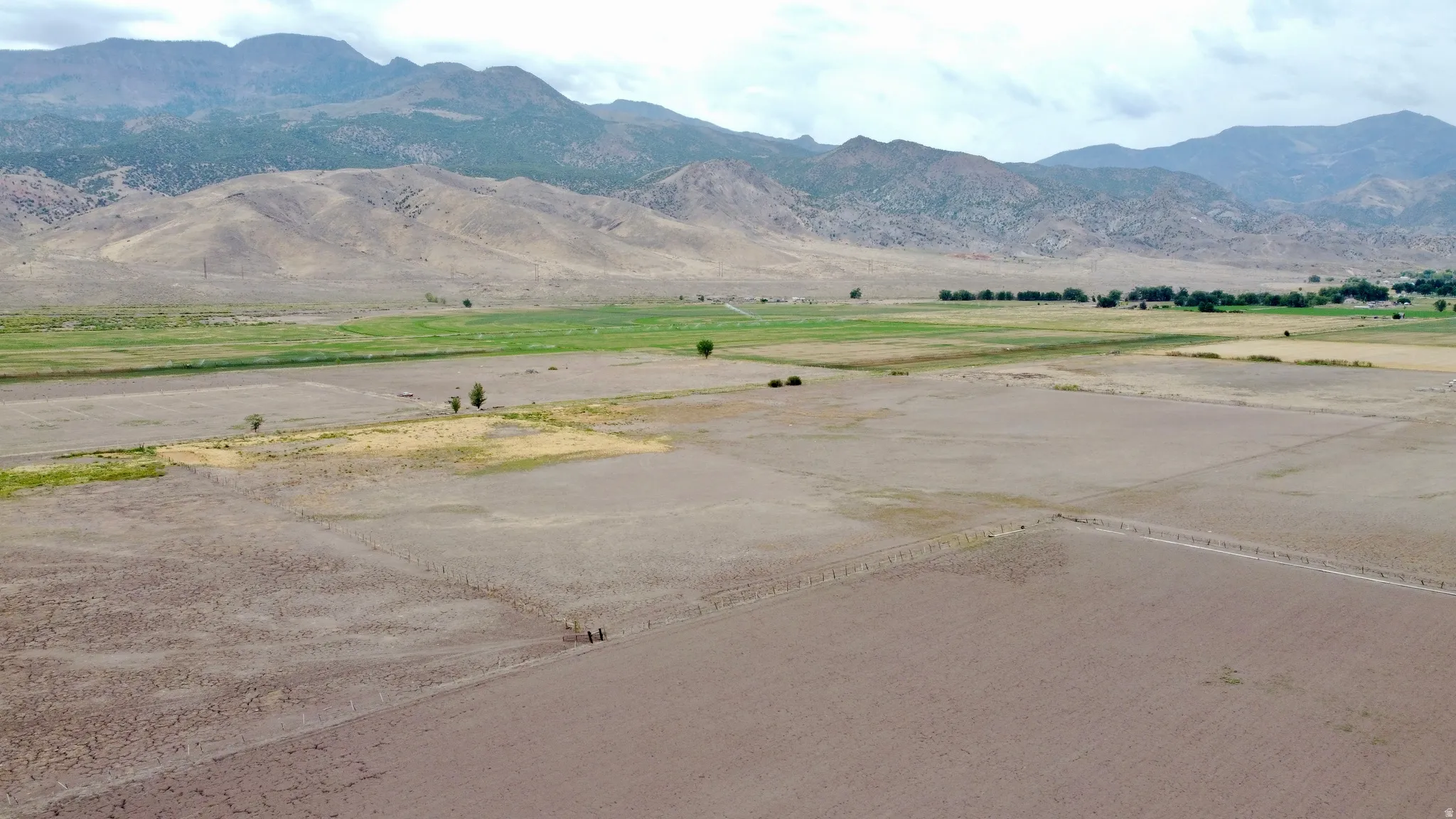 Expansive land parcel featuring a mix of cultivated and natural terrain, bordered by distant mountains