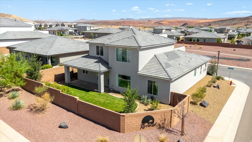 Two-story residence featuring a gray tile roof, stucco exterior, and a covered back patio