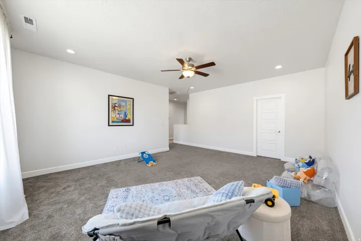 Recessed lighting, ceiling fan, white paneled door, light gray carpeting, and neutral wall tones