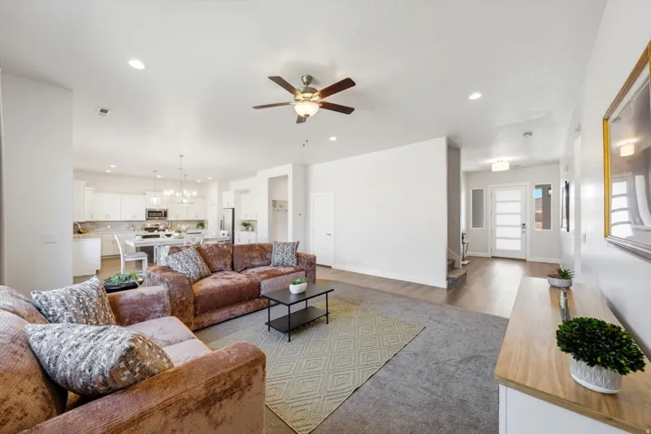 Recessed lighting, wood-finish flooring, ceiling fan, white kitchen cabinetry, and pendant light fixtures