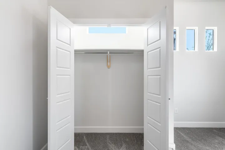 Recessed closet with double panel doors and integrated hanging rod, complemented by high-set rectangular windows