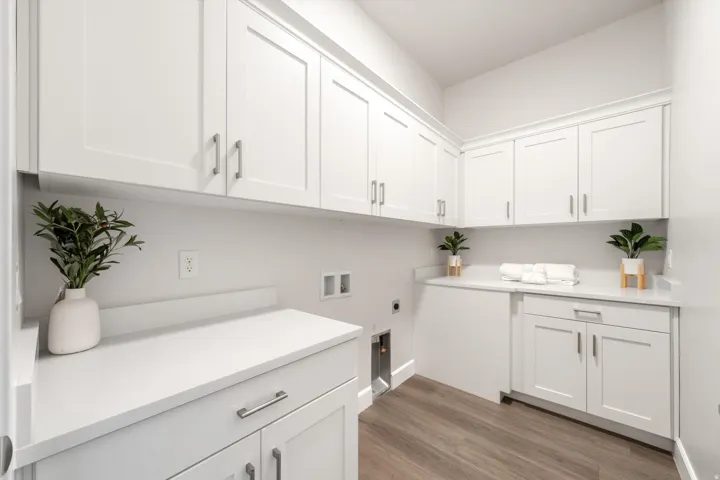 White shaker cabinetry with brushed nickel hardware, white countertops, and wood-finish flooring