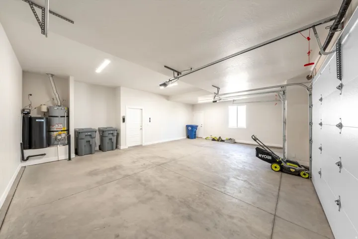 Spacious garage with a concrete floor, overhead lighting, and white walls