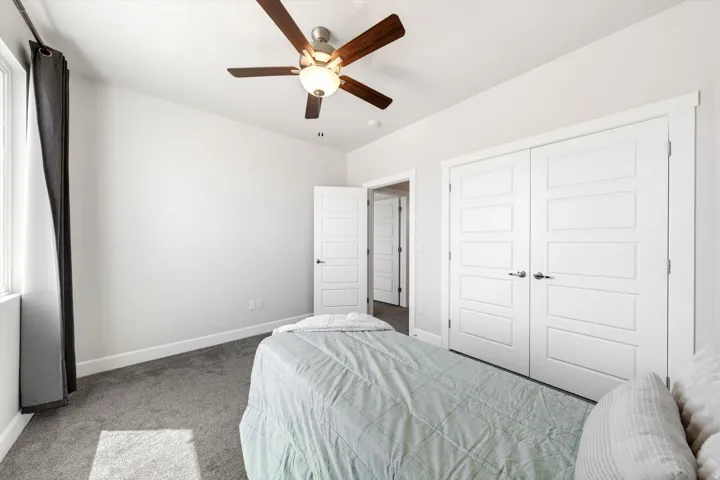 Neutral wall color, carpet flooring, a ceiling fan with light fixture, and white paneled closet doors