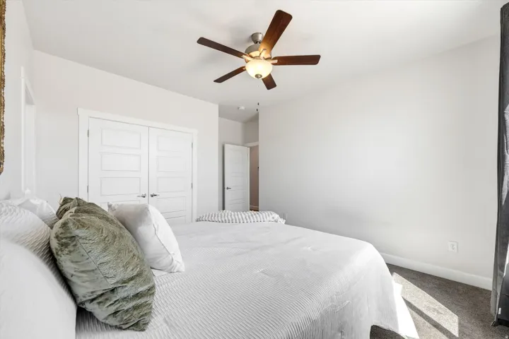 White walls, high ceilings, dark-finish ceiling fan with integrated lighting, wood-panel doors, and gray carpet
