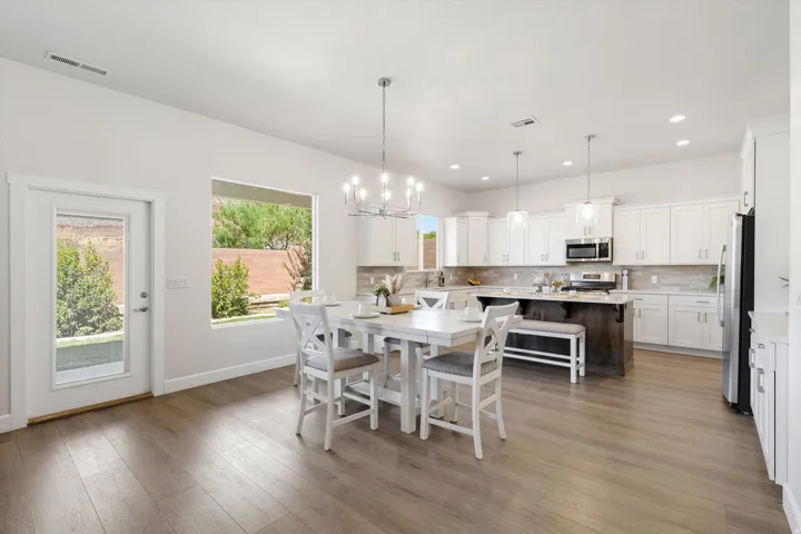 Spacious kitchen featuring white cabinetry, a large island with dark wood-finish base, stainless steel appliances, and wood-finish flooring