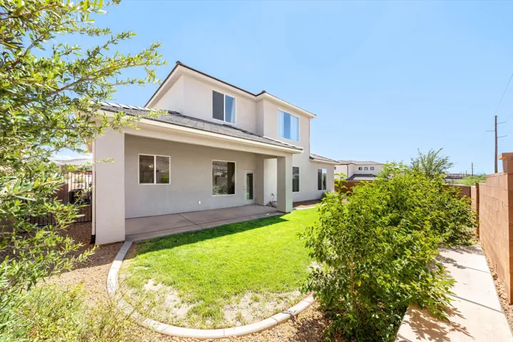 Expansive backyard featuring a covered patio, manicured lawn, and mature landscaping