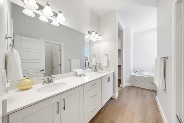 Dual vanity with white cabinetry, polished chrome hardware, and undermount sinks