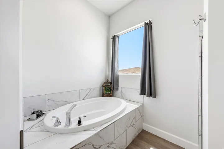 Built-in soaking tub with chrome fixtures, surrounded by marble-look tile