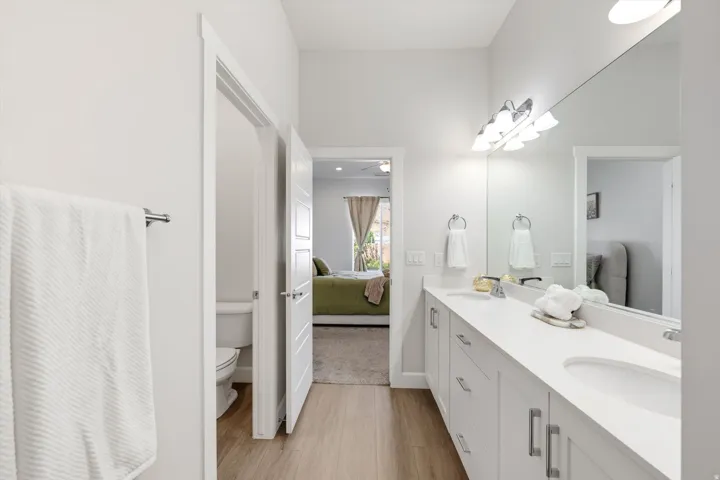 Double vanity with undermount sinks, white cabinetry, and a full-width mirror