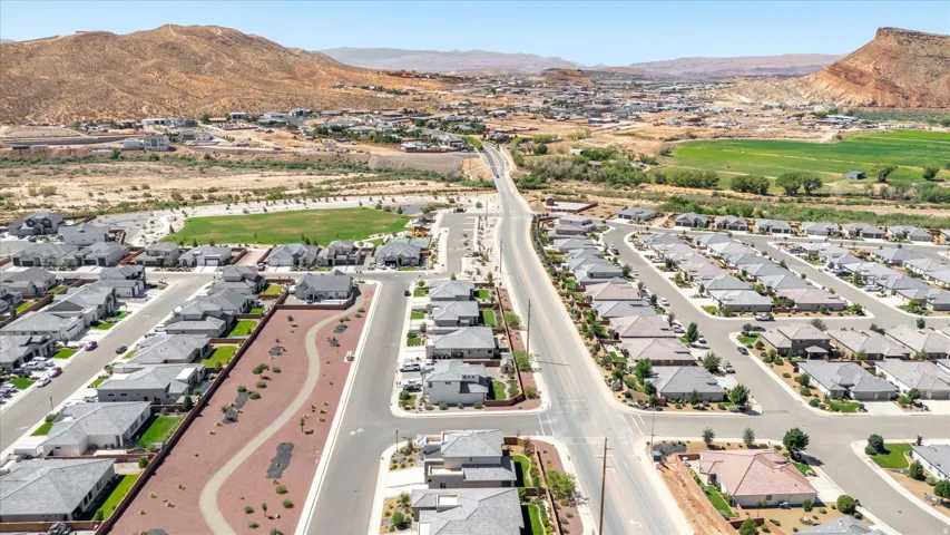 Residential development featuring multiple single-story homes, paved streets, and landscaped common areas
