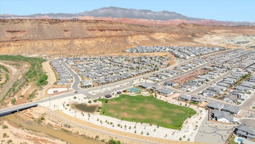 Community green space with a pond and sports courts, surrounded by residential properties, with a river and natural desert landscape in the background