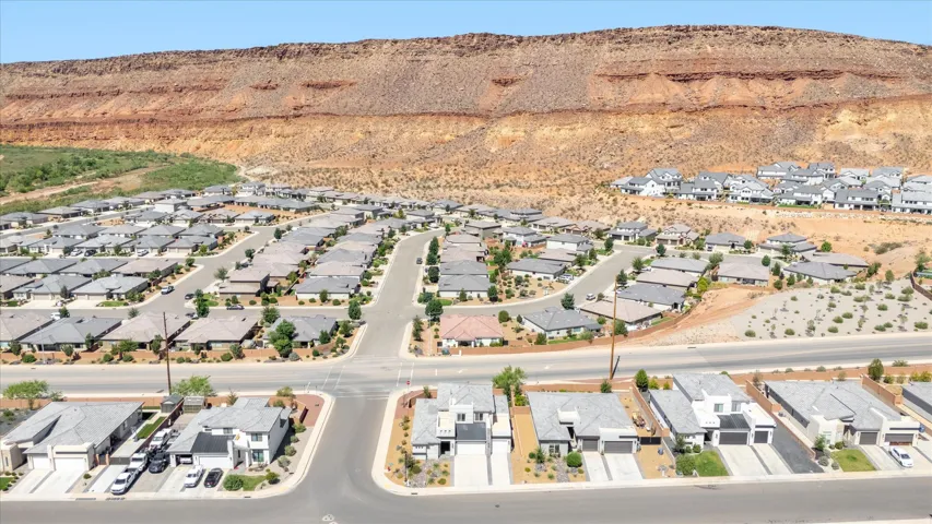 Residential community with multiple single-story and two-story homes featuring light-colored exteriors and dark-toned roofs