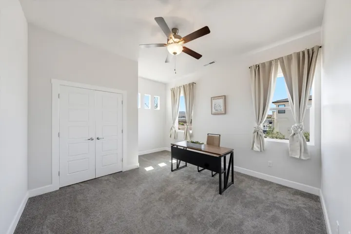 Spacious room featuring vaulted ceilings, a ceiling fan, and carpeted flooring