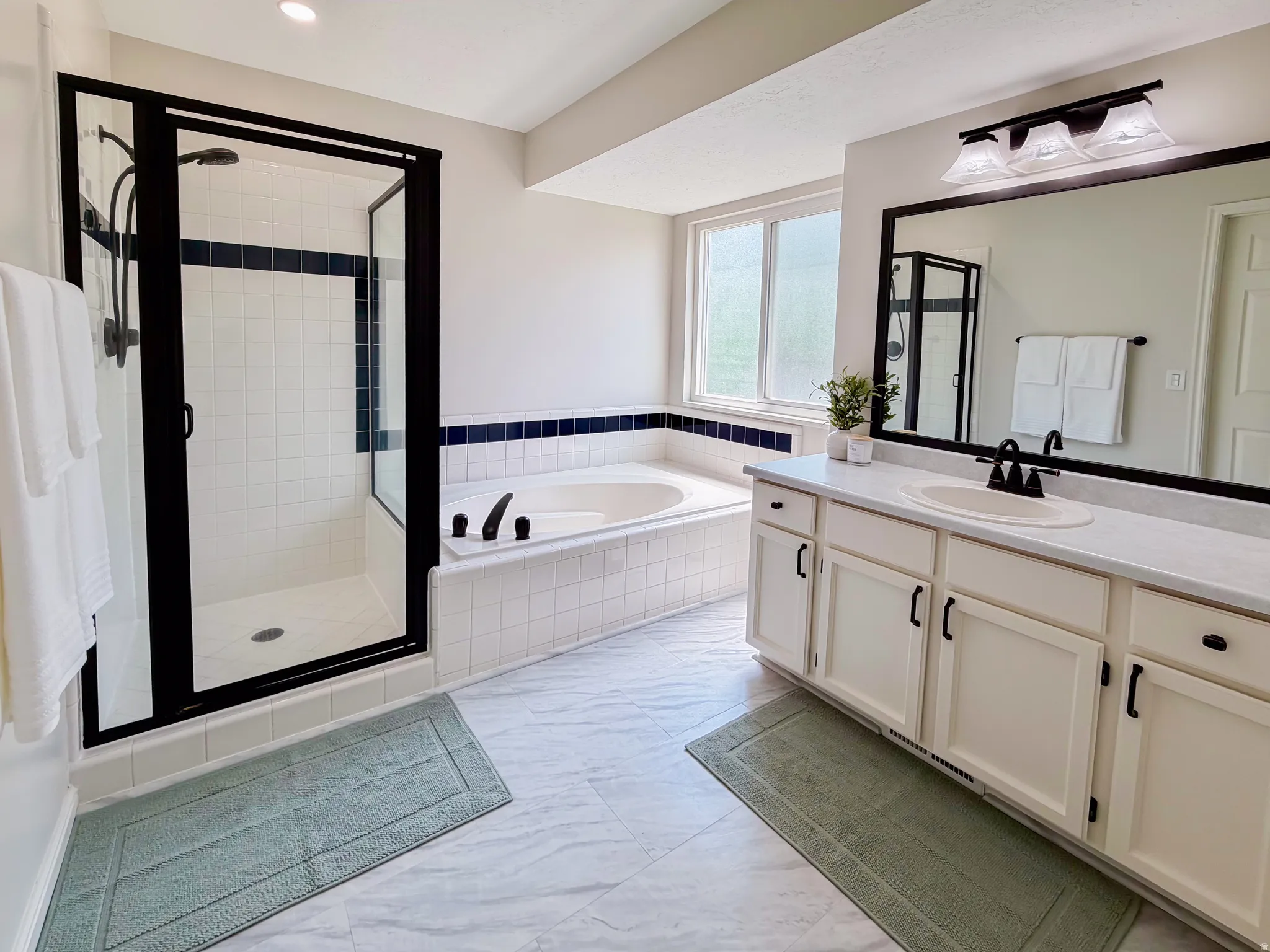 Dual vanity with integrated sinks, framed mirror, and three-light fixture