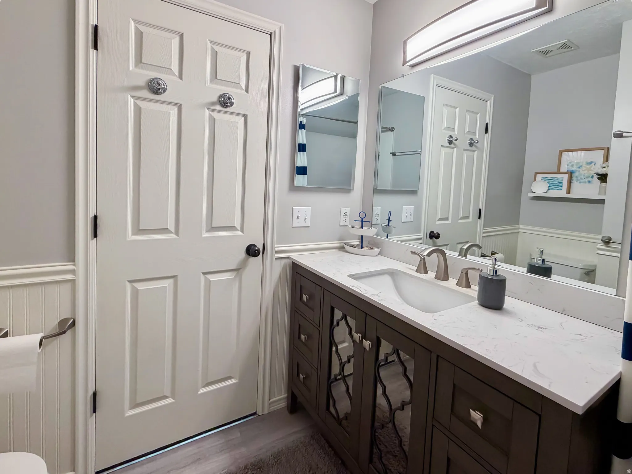 Bathroom featuring a contemporary vanity with an integrated sink, light-toned countertop, and brushed nickel fixtures