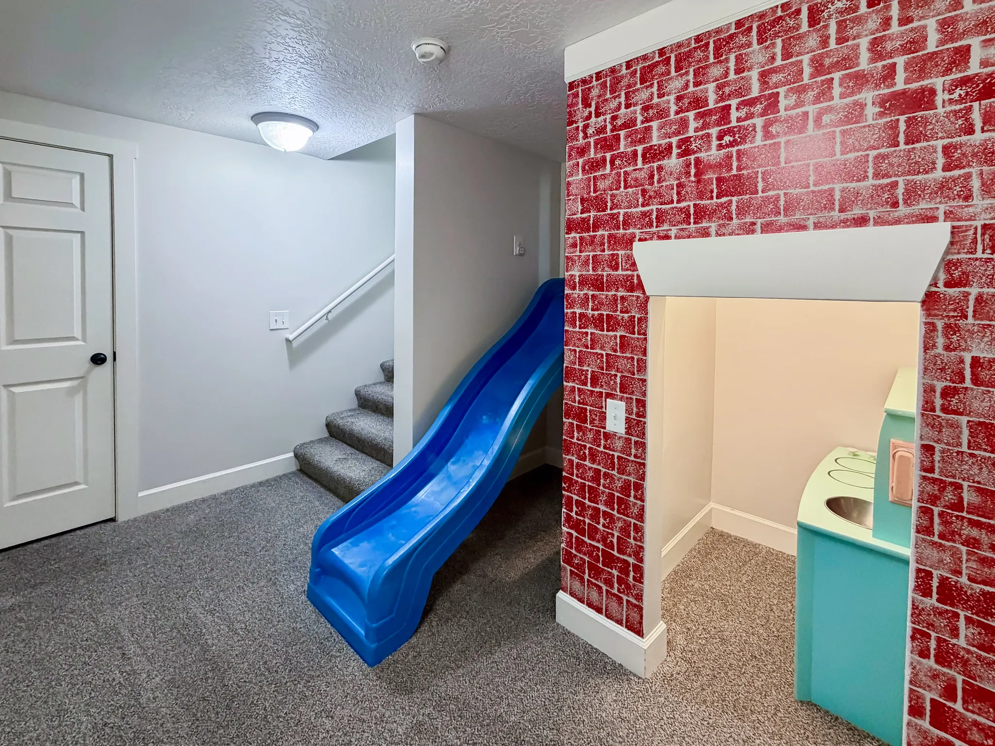 Carpeted flooring, painted white trim, and a brick-patterned accent wall