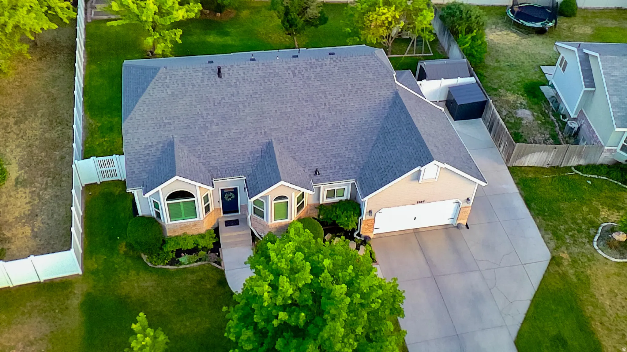 Single-story residence featuring a shingle roof, attached garage, well-maintained lawn, and a fenced perimeter
