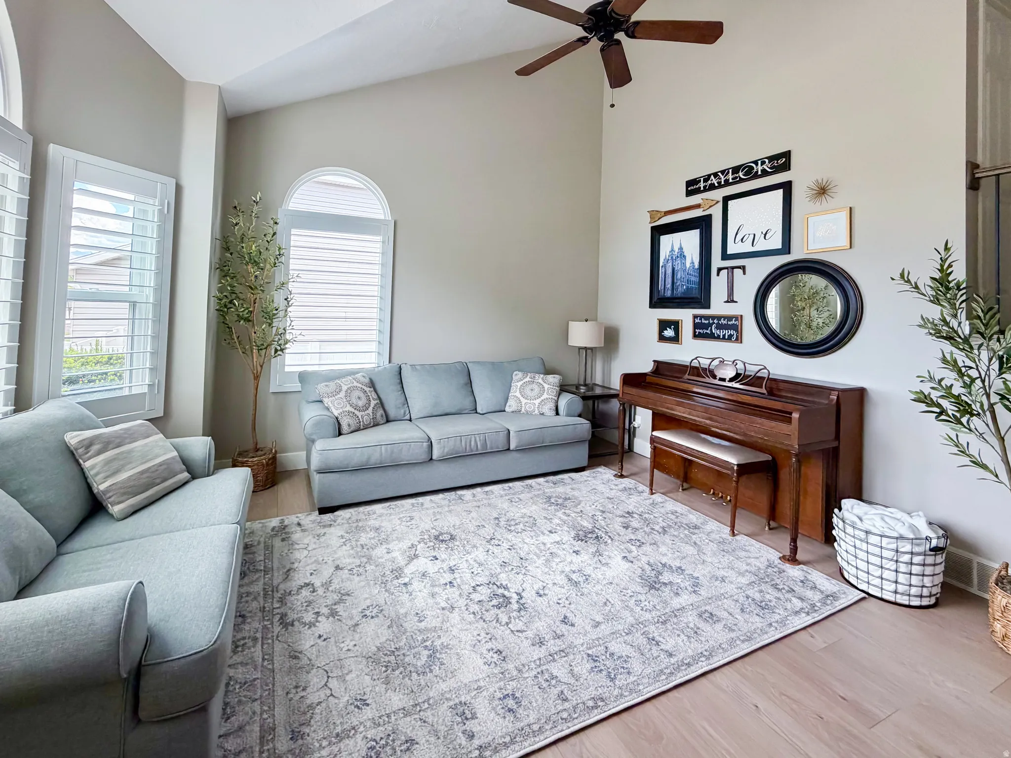 Vaulted ceilings, wood-finish flooring, plantation shutters, arched window, and a ceiling fan with integrated lighting