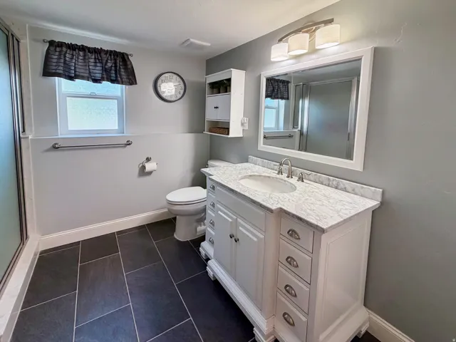 White vanity with a stone countertop, undermount sink, and brushed nickel fixtures