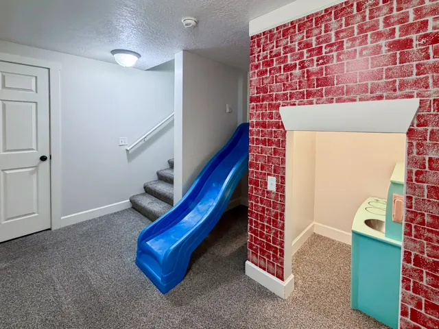Carpeted flooring, painted white trim, and a brick-patterned accent wall