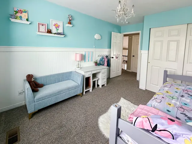Wall-mounted shelving, beadboard wainscoting, overhead chandelier, and carpeted flooring