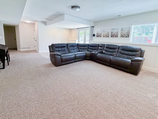 Spacious room with neutral carpeting, white walls, and wainscoting