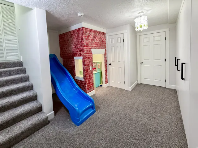 Carpeted flooring, white six-panel doors, and a built-in play structure with a brick-patterned accent wall