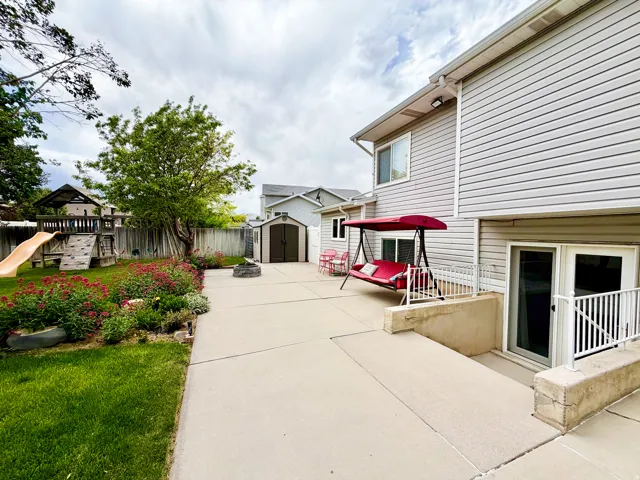 Spacious concrete patio with direct access to lower level, perimeter landscaping, and a separate storage shed