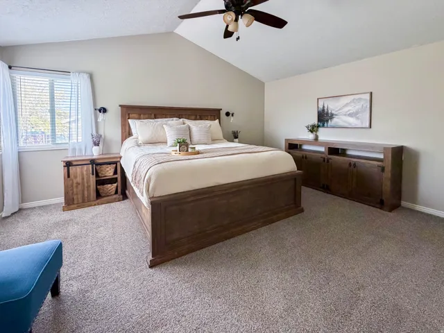 Vaulted ceiling with a ceiling fan, recessed window with blinds, wood-finish flooring, and built-in wood-finish cabinetry