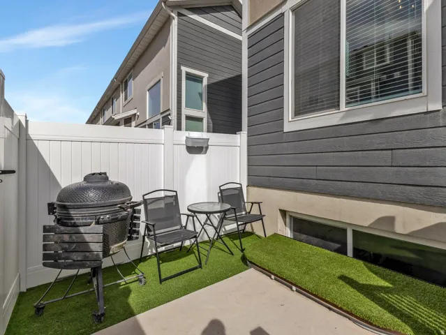 Private patio featuring white privacy fencing, artificial turf, and concrete paving