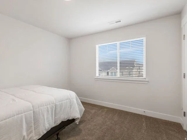 Recessed ceiling lighting, a large window with horizontal blinds, neutral wall paint, and textured carpeting