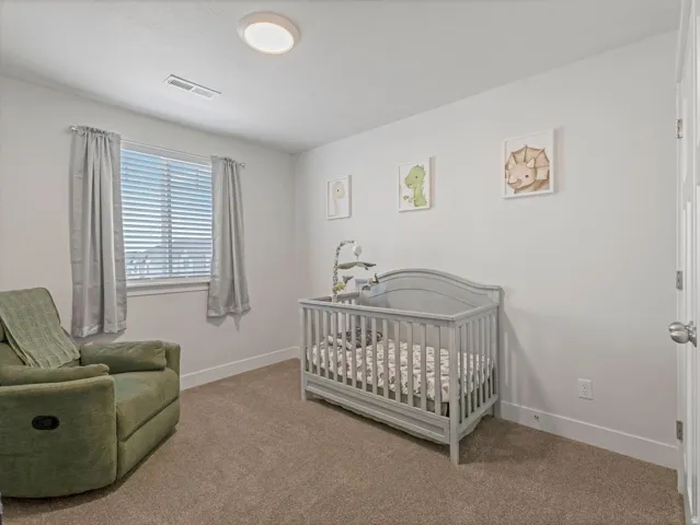 Carpeted room featuring a window with blinds, white walls, and a flush-mount ceiling light fixture