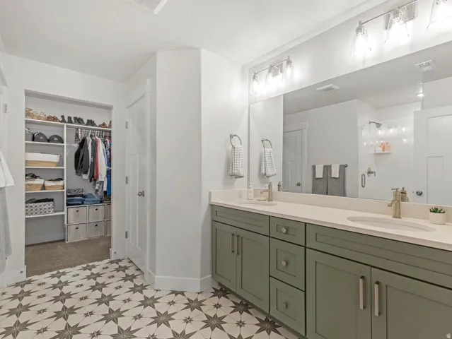 Dual vanity with sage green cabinetry and brushed nickel hardware, expansive countertop, and a full-width mirror