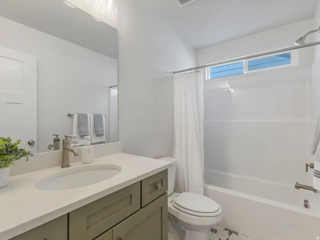 Bathroom featuring a single vanity with a light-colored countertop, an undermount sink, and a framed mirror